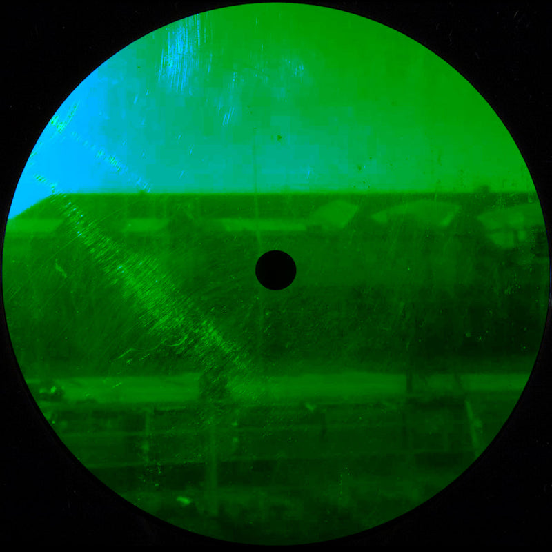 Green-tinted viewfinder or scope with a black dot in the center, on a dark background.